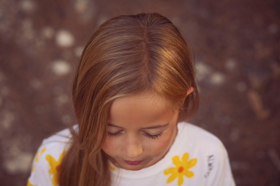 retrato de niña mirando hacia abajo durante sesión de fotos familiar en Zaragoza en exterior