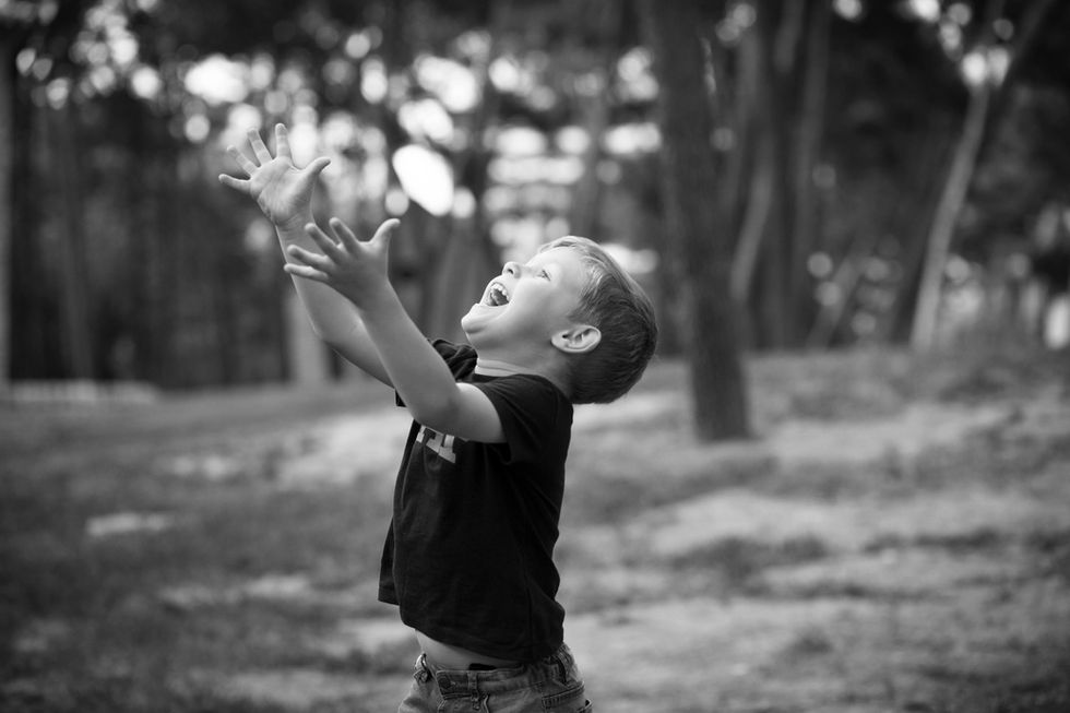 niño jugando y levantando los brazos en sesión de fotos familiar en Zaragoza al aire libre