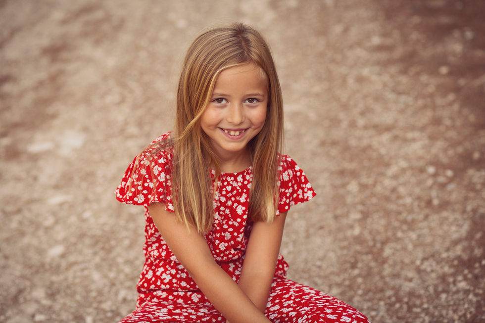 niña sonriendo sentada en el suelo durante sesión de fotos familiar en Zaragoza