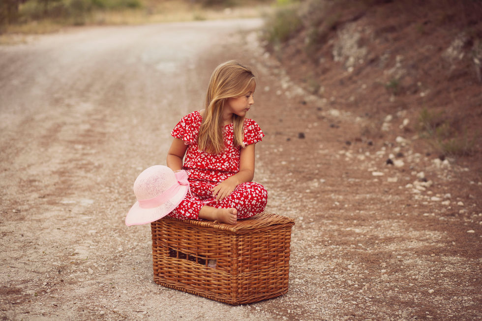 niña sentada sobre caja de madera en camino durante sesión de fotos familiar en Zaragoza