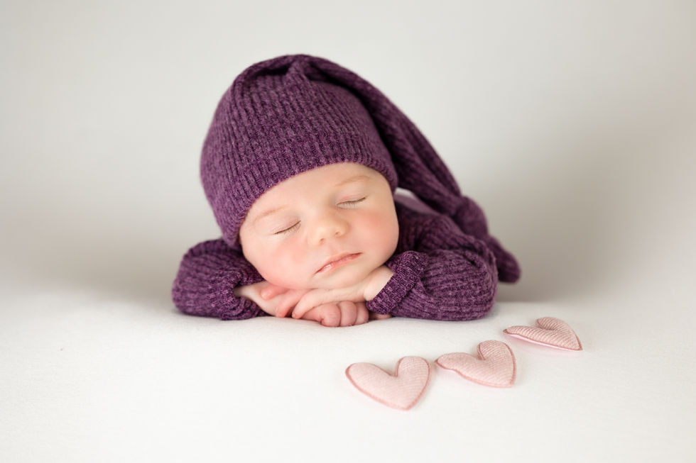 Fotografía newborn en Zaragoza de bebé recién nacido dormido con gorro morado en estudio