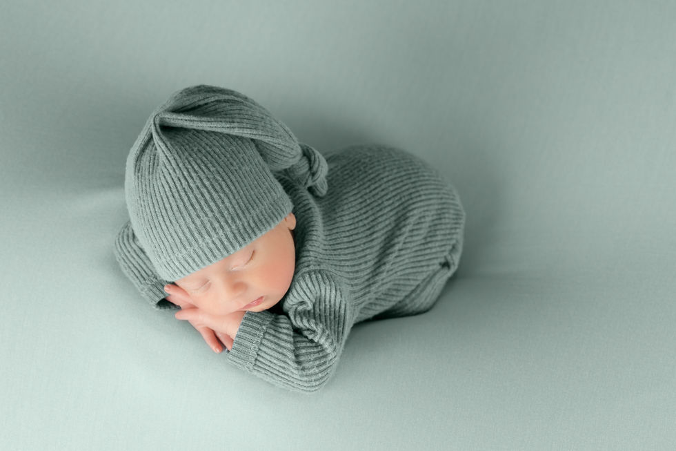 Reportaje newborn en Zaragoza con bebé recién nacido envuelto en tonos grises sobre fondo neutro