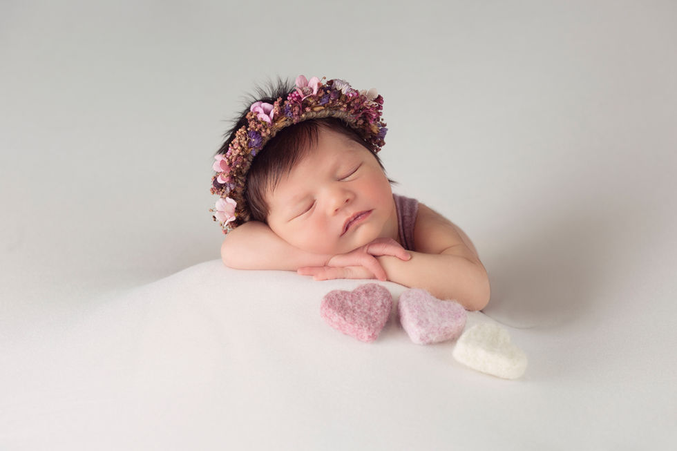 Bebé recién nacido dormido con corona de flores en sesión newborn en Zaragoza