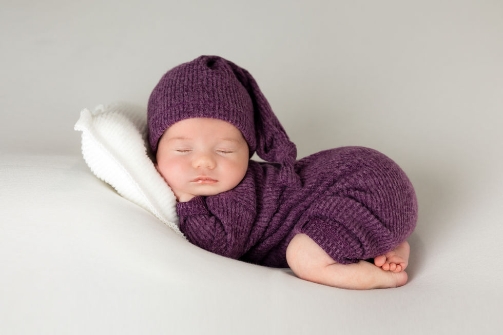 Fotografía newborn en Zaragoza de bebé recién nacido envuelto en tela morada sobre fondo neutro
